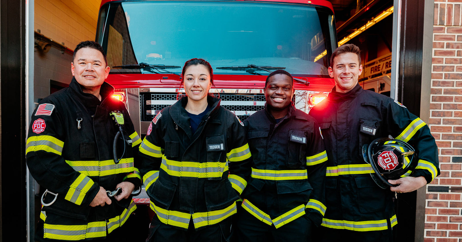 Group of firefighters standing together in front of a fire truck.