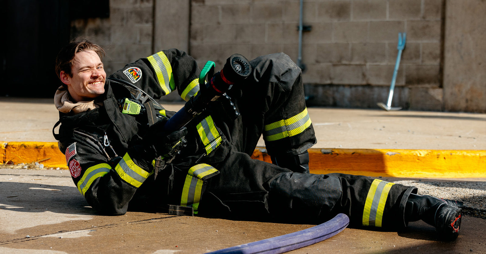 Firefighter on the ground posing with a fire hose.