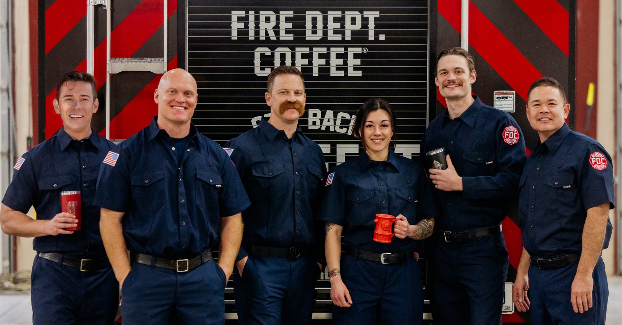 The Fire Dept. Coffee Video Team standing together behind a fire truck.