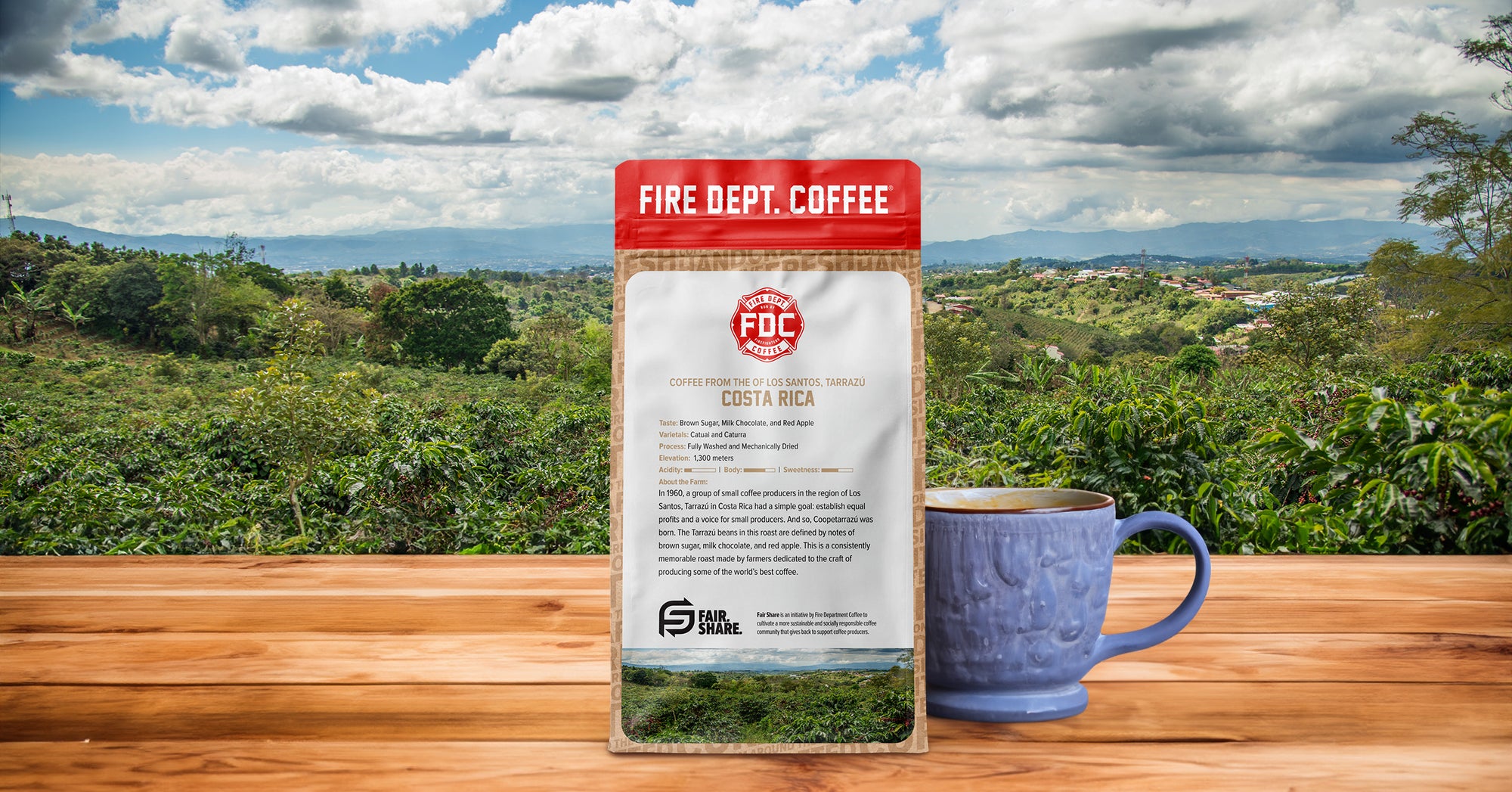 A bag of coffee next to a handmade coffee cup with a coffee farm in the background.