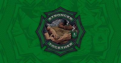 An illustration depicting two firefighters sitting at a kitchen table having a conversation set within a Maltese cross on a green background.