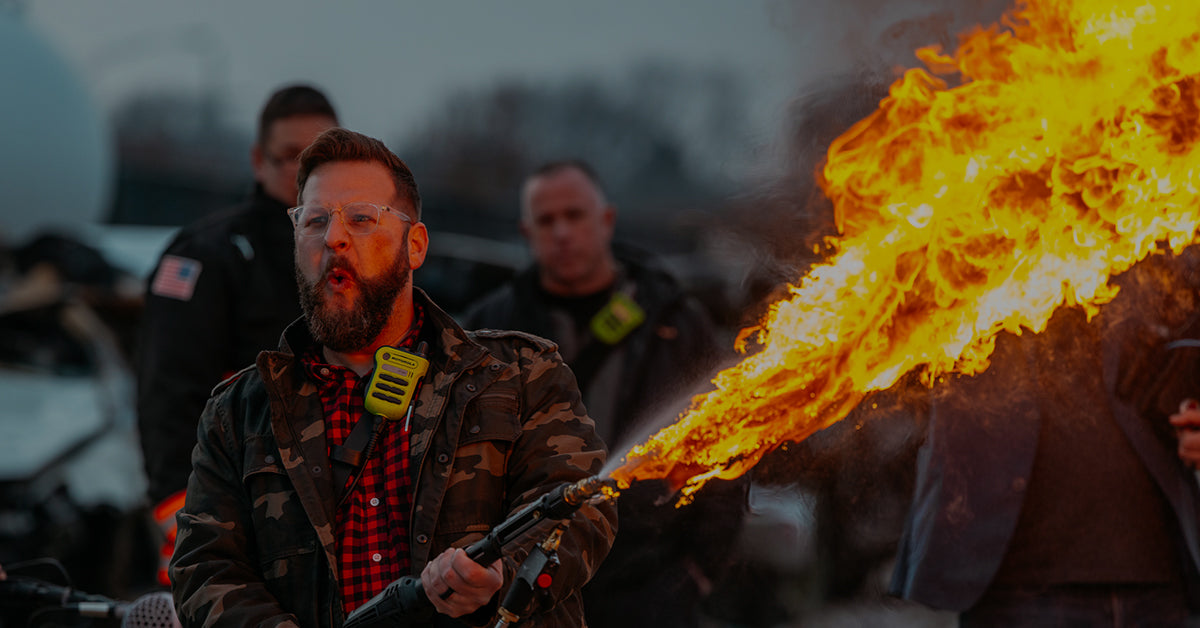 Photo of Brad Flaherty, Fire Dept. Coffee's CMO and Creative Director, holding a flamethrower with flames shooting out.