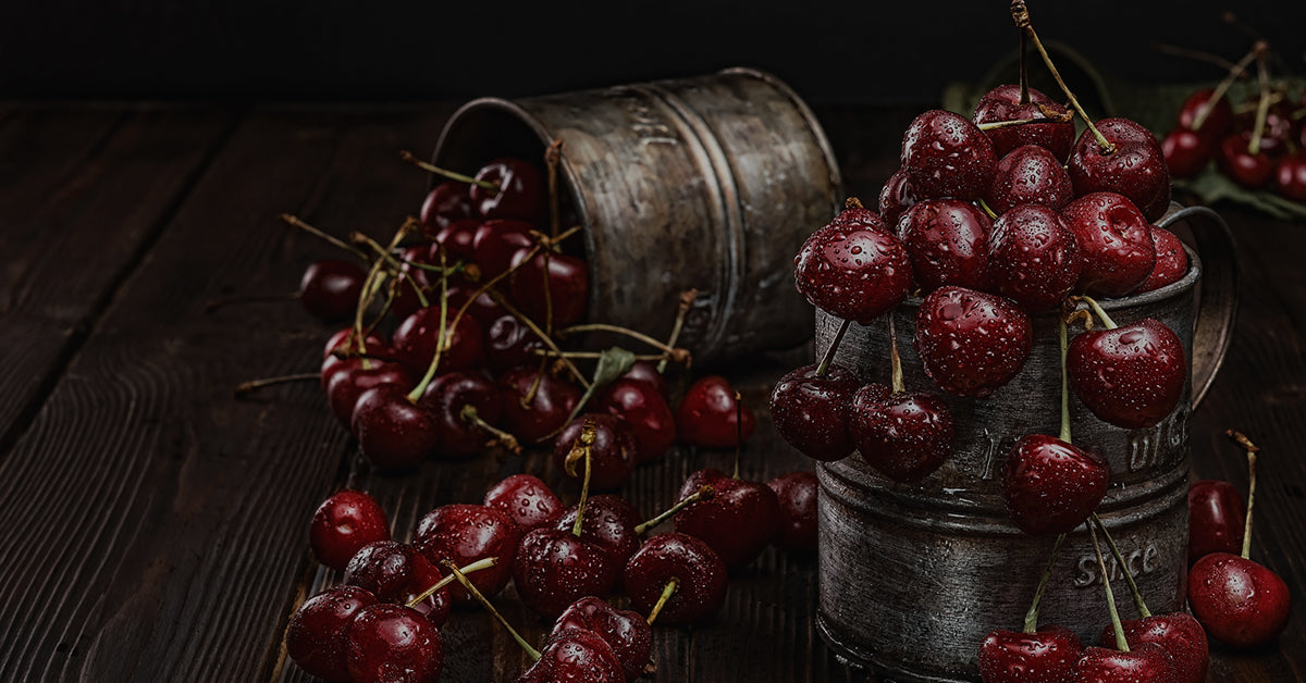 Photograph of cherries overflowing out of two metal buckets