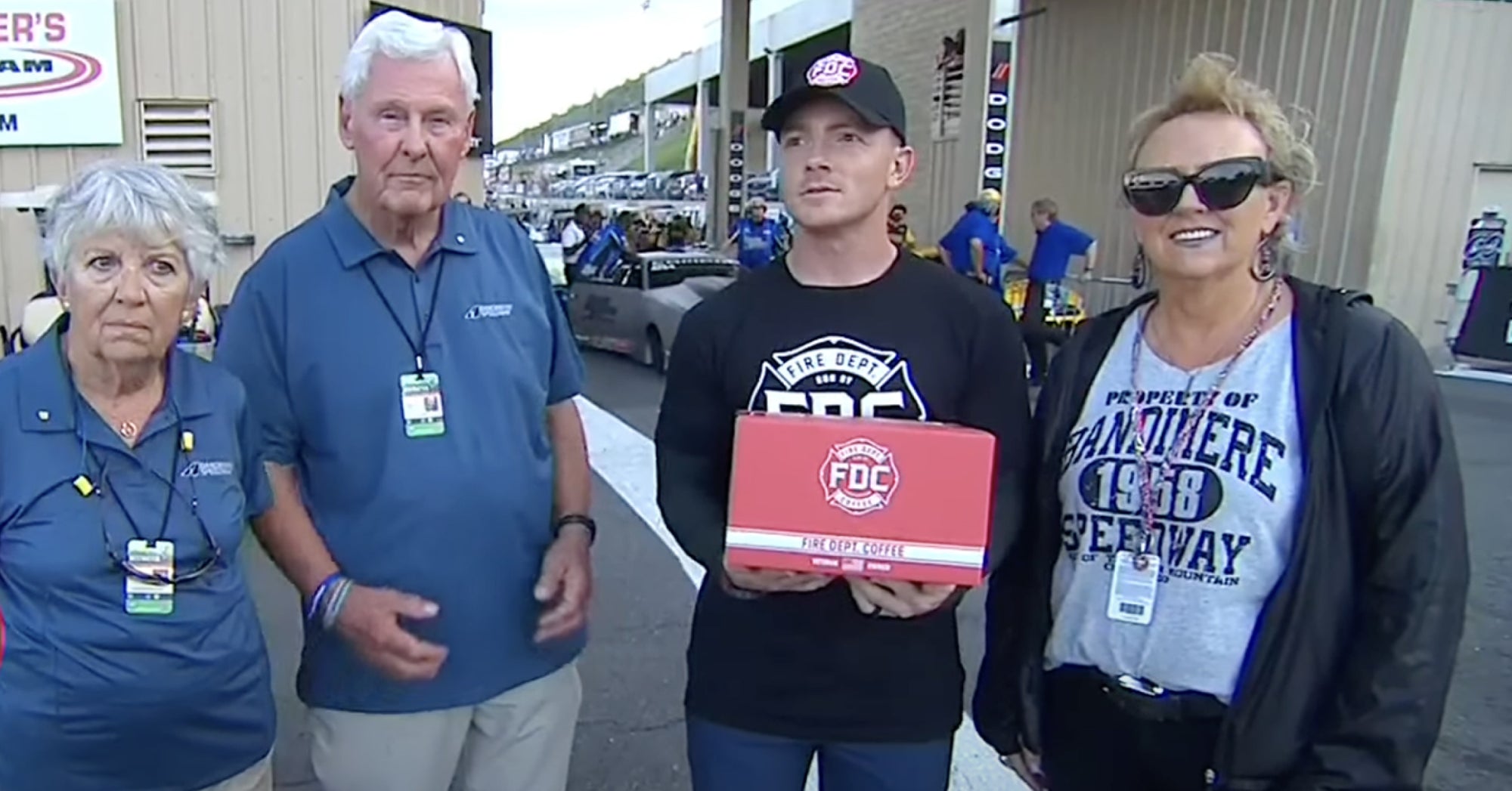 Group of 4 people at the NHRA race in Denver during the Community Hero award presentation.