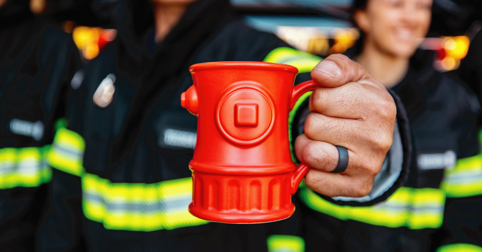 Fire hydrant mug in red held by a firefighter in uniform.