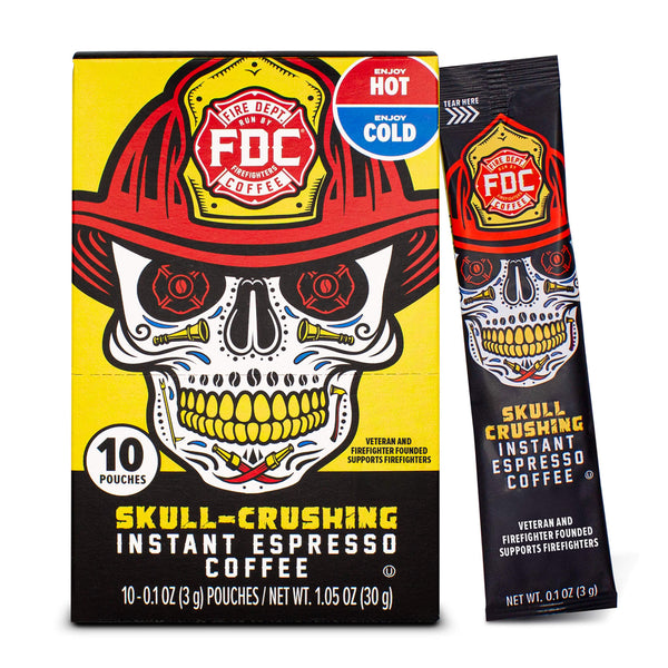 A box and single stick pack of FDC Fire Department Skull-Crushing Instant Espresso Coffee, featuring a graphic of a skull wearing a firefighter helmet on a yellow and black background.