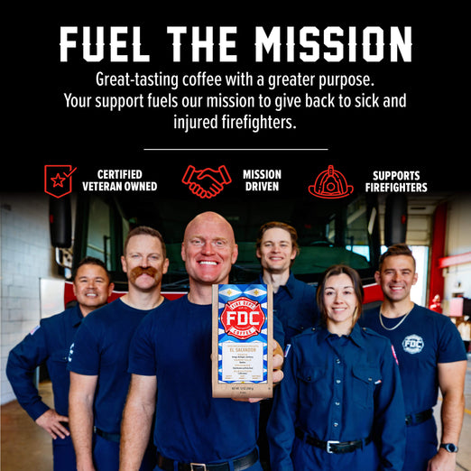 A group of firefighters in navy uniforms stand in a fire station holding a bag of FDC Fire Department Certified coffee. The top of the image features a black banner with white text reading ’FUEL THE MISSION’ and supporting features like ’CERTIFIED VETERAN OWNED’, ’MISSION DRIVEN’, and ’SUPPORTS FIREFIGHTERS’.