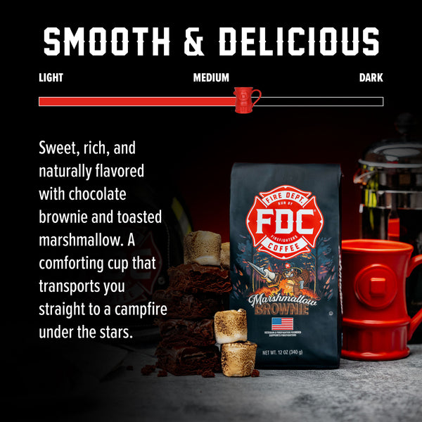 A bag of Fire Department Coffee's 12 oz Marshmallow Brownie Coffee with a red section accross the top that says "Fire Dept. Coffee". The art on the bag features a beaver holding a pike pole with a marshmallow and brownie on it over a campfire. The title reads, "Marshmallow Brownie" and there is a veteran owned badge with an American flag in the bottom right corner.