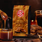 FDC Butter Toffee Bourbon coffee bag with a cup of coffee and caramel sauce on a wooden surface.