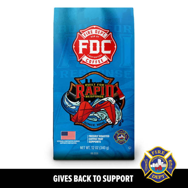 A blue bag of FDC Fire Department Coffee featuring a red fire department emblem and an illustration of a fire truck and firefighter gear, with the text 'GIVES BACK TO SUPPORT' below on a black background.