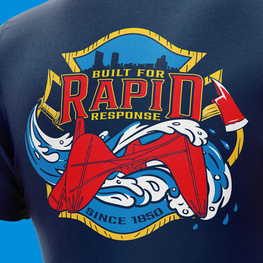 Close-up of a navy blue T-shirt showing a large red, yellow, and blue graphic on the chest with the words ’Built for Rapid Response’ and ’Since 1850’.