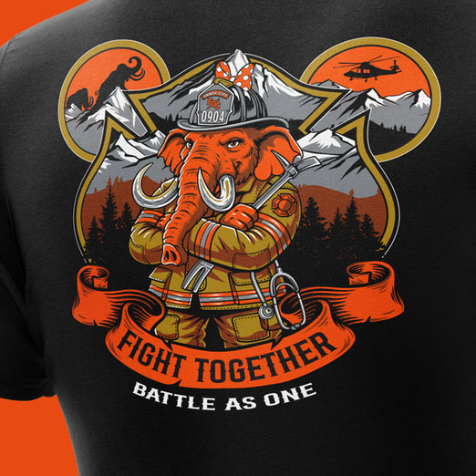Close-up of a black T-shirt featuring a large firefighter-themed graphic with an orange elephant in a helmet, mountains, trees, and the text ’FIGHT TOGETHER BATTLE AS ONE’.