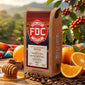 FDC Coffee package with coffee beans, oranges, and a honey dipper on a wooden table.
