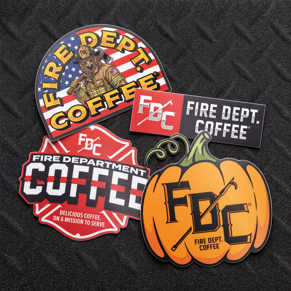 Four FDC Fire Department Coffee stickers shown on a white background with a black banner reading 'Sticker Club Pack | October 2026'. The stickers include an arched firefighter-themed coffee logo, a red-and-black FDC logo, a red-and-white fire department coffee logo, and an orange pumpkin sticker with FDC lettering.