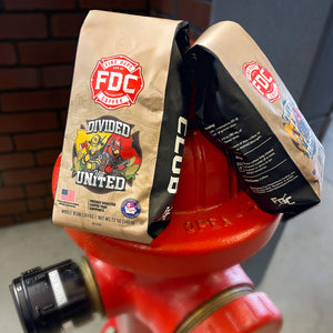 A bag of FDC Coffee 'Divided But United' fresh roasted coffee on a white background with a black banner at the bottom reading 'GIVES BACK TO SUPPORT' and a FIA Firefighters Association logo in the lower right corner.