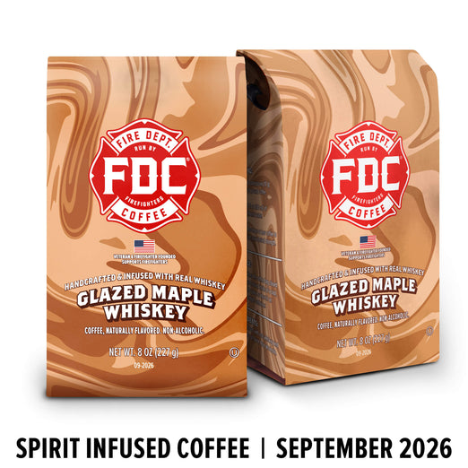 Two bags of FDC Fire Department Bar Coffee Glazed Maple Whiskey coffee with a brown liquid swirl design, shown on a white background with a black text banner at the bottom reading ’SPIRIT INFUSED COFFEE | SEPTEMBER 2026’.
