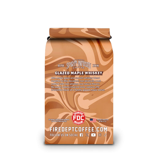 A coffee bag labeled ’Spirit Infused Coffee’ with ’Glazed Maple Whiskey’ flavor. The packaging features a glossy, swirling maple brown pattern in shades of orange, tan, and brown, with white text and a red FDC Certified logo near the bottom.