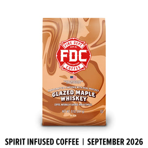 A bag of FDC Fire Department Coffee Glazed Maple Whiskey on a white background, with a black banner at the bottom reading 'SPIRIT INFUSED COFFEE | SEPTEMBER 2026'. The bag features a brown and beige swirl pattern with a red FDC logo.