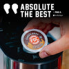 A hand inserts a round coffee K-cup pod into a coffee maker. The pod label reads 'Donut Shop FDC Coffee' and the image includes large text at the top that says 'ABSOLUTE THE BEST' with a quote attribution to Paul G.