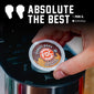 A hand inserts a round coffee K-cup pod into a coffee maker. The pod label reads ’Donut Shop FDC Coffee’ and the image includes large text at the top that says ’ABSOLUTE THE BEST’ with a quote attribution to Paul G.