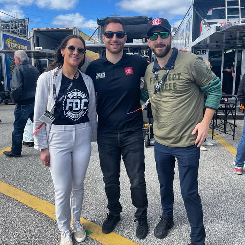 Driver Kaz Grala standing with Fire Department Coffee team members