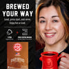 A promotional graphic for FDC Brewing's Spirit Infused Coffee showing a smiling woman on the right holding a red mug, alongside product information on the left including the text 'BREWED YOUR WAY,' a coffee pod maker icon, and a coffee pod box. The background is split between black on the left and a warm indoor setting on the right.