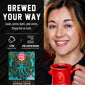 A promotional graphic for a coffee pod maker showing a smiling woman on the right holding a red mug, and product text plus a pod package illustration on the left. The text reads ’BREWED YOUR WAY’ and ’Load, press start, and serve.
