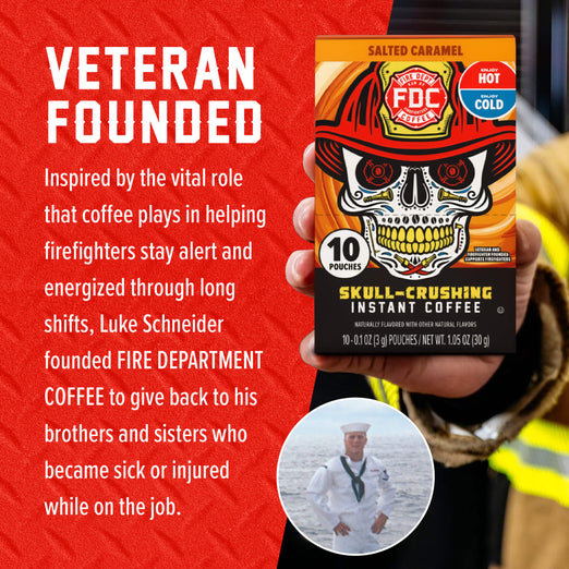 A hand holds a box of Fire Department Coffee Salted Caramel Instant Coffee against a red promotional background with white text. The box features a skull wearing a firefighter helmet, and the image includes a circular inset photo of a man in a sailor uniform and a headline reading ’VETERAN FOUNDED.