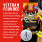 A hand holds a box of Fire Department Coffee Salted Caramel Instant Coffee against a red promotional background with white text. The box features a skull wearing a firefighter helmet, and the image includes a circular inset photo of a man in a sailor uniform and a headline reading ’VETERAN FOUNDED.