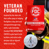 A hand holds a red box of Fire Department Coffee Original Medium Roast against a promotional graphic with white text on a red textured background and a small circular photo inset. The box prominently shows the brand name FDC and product details.
