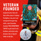 A hand holds a box of FDC Fire Department Coffee Shellback Espresso Coffee against a red promotional background with white text about veteran funding for firefighters. A small circular inset shows a man in a white sailor uniform standing at a harbor.