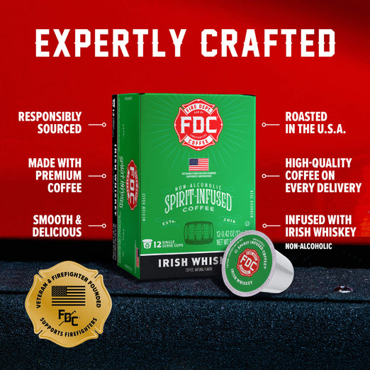 FDC Fire Department Spirit Infused Coffee box in green with a single matching coffee capsule in front, set on a dark textured surface against a red background with promotional text and a gold veteran-recognized seal.