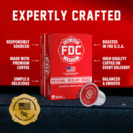 A red box of FDC Fire Department Coffee Original Medium Roast coffee is shown on a dark textured surface against a red background, with a single coffee capsule placed in front. White text around the product highlights features like expertly crafted, responsibly sourced, made with premium coffee, roasted in the U.