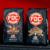 A Marshmallow Brownie Coffee bag and a Cinnamon French Toast Coffee bag on the bumper of a fire truck with a red background. 