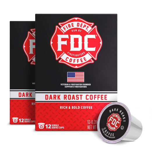 A box of FDC Fire Department Coffee Dark Roast Coffee, shown with two additional boxes behind it and a single coffee capsule in front on a plain white background.