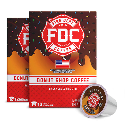 Three boxes of FDC Fire Department Coffee Donut Shop Coffee with one single-serve coffee pod shown in front on a white background.