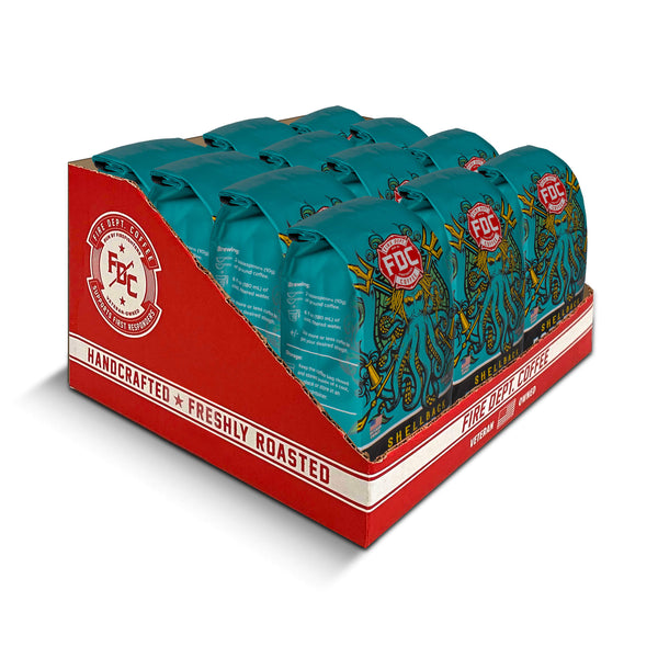 A 12-ounce package of Fire Department Coffee's Shellback Espresso Roast on a table with a red FDC tumbler and a small anchor.