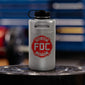 Lifestyle photo featuring a 64oz silver stainless steel Fire Department Coffee Growler with Fire Department Coffee logo facing forward. 