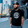 A lifestyle image of someone wearing the Fire Department Coffee Black Shirt. The front of the shirt features the FDC maltese cross logo in white.