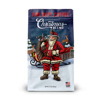 A 12 ounce bag of Fire Department Coffee Christmas Blend featuring an illustration of Santa holding a fire hydrant coffee mug and a bag full of firefighter tools