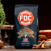 A 12 oz bag of Cinnamon French Toast Coffee from Fire Department Coffee on a table next to a plate of French toast.