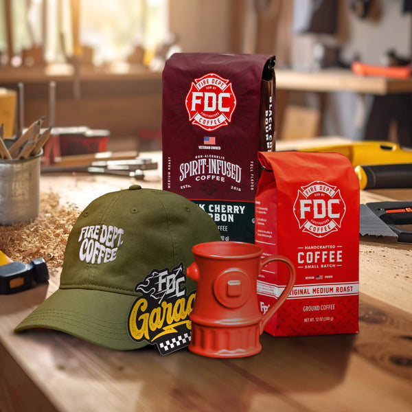 A bag of Black Cherry Bourbon coffee and medium roast coffee with a red fire hydrant mug, green dad hat and sticker in front on a white background.