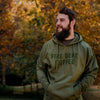 A lifestyle image of someone wearing the FDC Military Green Hoodie. The front says "Fire Dept. Coffee" in dark green lettering.