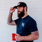 A lifestyle image of someone wearing an FDC keystone hat in black and holding a fire hydrant coffee mug.