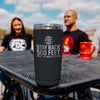 A 20 oz black tumbler that reads STAY BACK 500 FEET UNTIL I'VE HAD MY COFFEE. The mug is sitting on an outdoor table.
