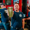 A man holding a 20 ounce green tumbler that has FIRE DEPT. COFFEE engraved on the front.