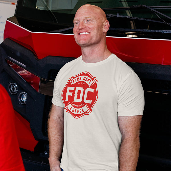 Five Fire Dept. Coffee T-shirts in pink, vintage white, navy, military green, and black, each featuring an FDC Maltese cross logo in various colors 