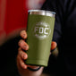 A person holding a green tumbler with the Fire Department Coffee logo, against a dark background.