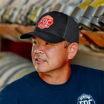 Side view of the front of the FDC black mesh hat with the FDC maltese cross logo on the front