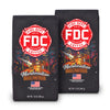 Two bags of Fire Department Coffee's 12 oz Marshmallow Brownie Coffee with a red section accross the top that says "Fire Dept. Coffee". The art on the bag features a beaver holding a pike pole with a marshmallow and brownie on it over a campfire. The title reads, "Marshmallow Brownie" and there is a veteran owned badge with an American flag in the bottom right corner.